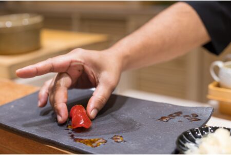 master sushi chef placing a piece of tuna sushi down on a plate at an omakase restaurant in hong kong