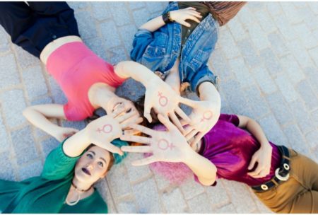 women holding up female symbols on hands