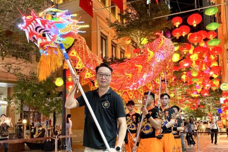 master kowk holding an led fired dragon with his team behind him