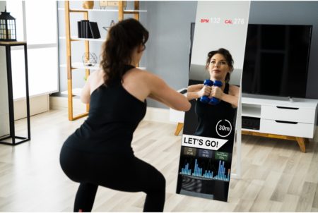 woman exercising using smart mirror to track her fitness stats