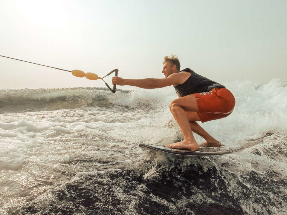 wake surfer getting pulled by a rope on a skim board